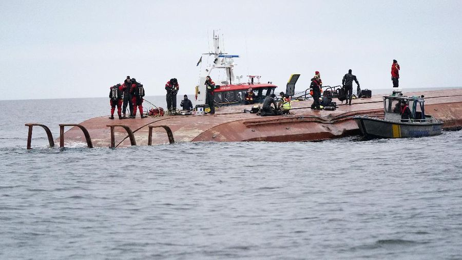 Divers work on the capsized Danish cargo ship Karin Hoej, right, after it collided with British cargo vessel Scot Carrier in the Baltic Sea, between Ystad and Bornholm, Sweden, Monday, Dec. 13, 2021. Two cargo ships collided in the Baltic Sea off southern Sweden and at least two people were reported missing Monday. One of the vessels capsized and will be towed to a Swedish port, authorities said. The maritime administration said it received a pre-dawn alarm that two cargo ships had collided south of Ystad in Sweden, close to the Danish island of Bornholm. The authority identified the ships as the Danish-flagged Karin Hoej and a British ship, the Scot Carrier. The Danish ship capsized fully and was floating upside down. (Johan Nilsson/TT via AP)