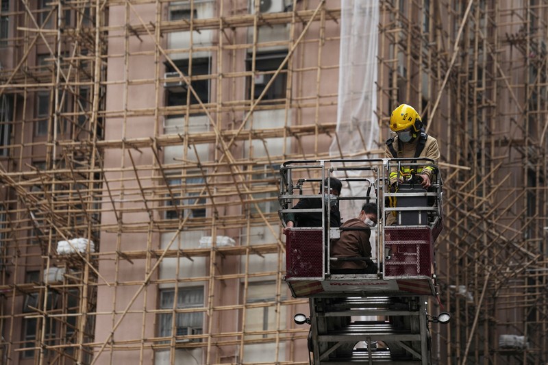 Seorang petugas pemadam kebakaran menyelamatkan orang-orang yang terjebak dari kebakaran yang terjadi di World Trade Center di Hong Kong (15/12/2021). (REUTERS/Lam Yik)