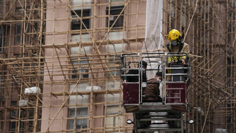Seorang petugas pemadam kebakaran menyelamatkan orang-orang yang terjebak dari kebakaran yang terjadi di World Trade Center di Hong Kong (15/12/2021). (REUTERS/Lam Yik)
