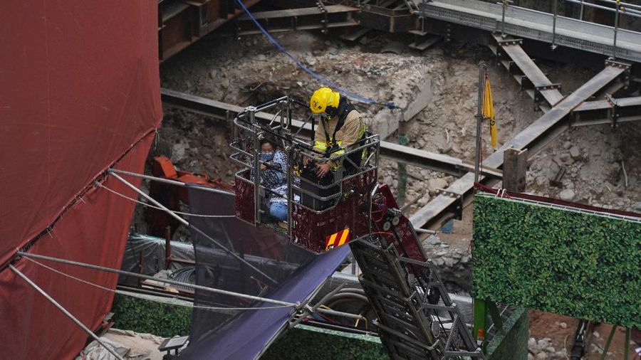 Seorang petugas pemadam kebakaran menyelamatkan orang-orang yang terjebak dari kebakaran yang terjadi di World Trade Center di Hong Kong (15/12/2021). (REUTERS/Lam Yik)