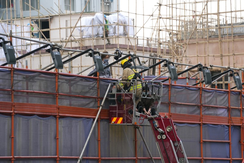 Kebakaran di gedung wtc Hong Kong Seorang petugas pemadam kebakaran menyelamatkan orang-orang yang terjebak dari kebakaran yang terjadi di World Trade Center di Hong Kong (15/12/2021). (REUTERS/Lam Yik)