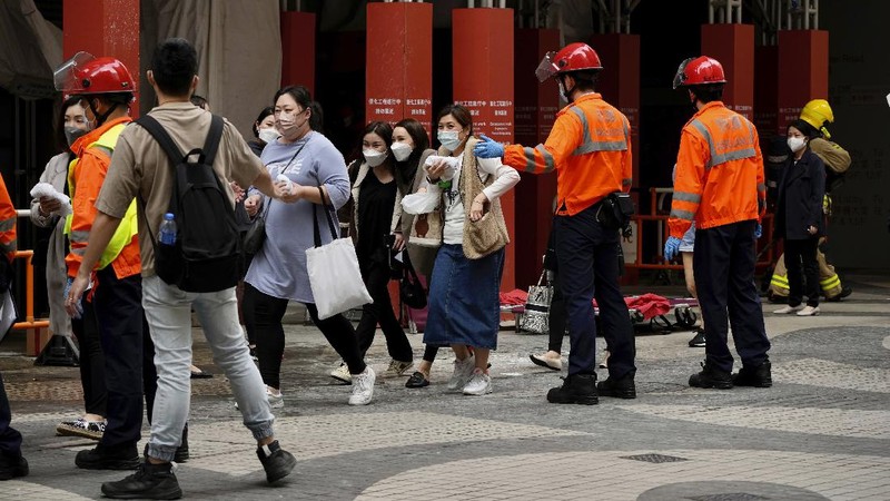 Seorang petugas pemadam kebakaran menyelamatkan orang-orang yang terjebak dari kebakaran yang terjadi di World Trade Center di Hong Kong (15/12/2021). (REUTERS/Lam Yik)