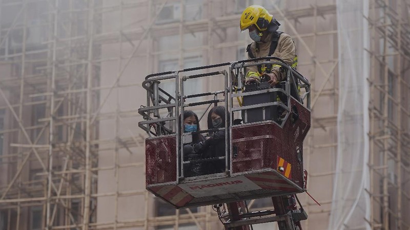 Seorang petugas pemadam kebakaran menyelamatkan orang-orang yang terjebak dari kebakaran yang terjadi di World Trade Center di Hong Kong (15/12/2021). (REUTERS/Lam Yik)