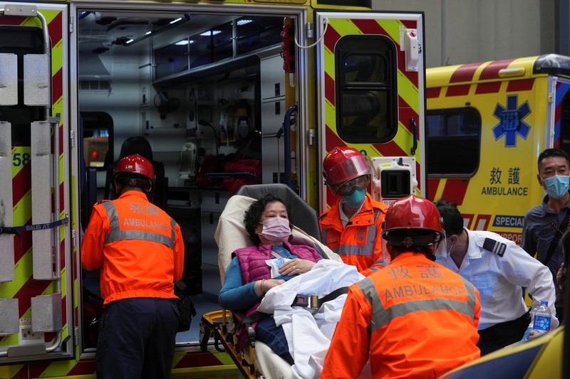 Seorang petugas pemadam kebakaran menyelamatkan orang-orang yang terjebak dari kebakaran yang terjadi di World Trade Center di Hong Kong (15/12/2021). (REUTERS/Lam Yik)