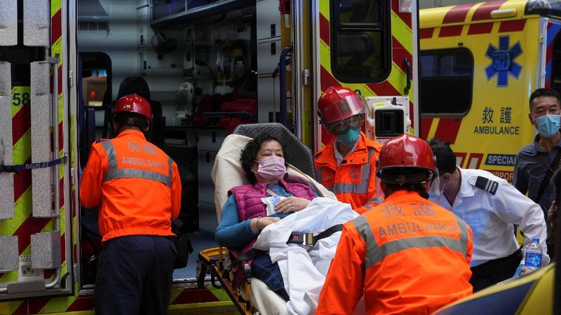 Seorang petugas pemadam kebakaran menyelamatkan orang-orang yang terjebak dari kebakaran yang terjadi di World Trade Center di Hong Kong (15/12/2021). (REUTERS/Lam Yik)