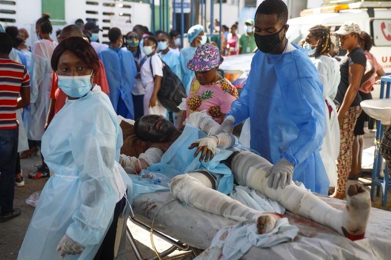 Kebakaran truk Bahan Bakar yang Meledak di Cap Haitien, Haiti Warga berdiri di tengah rumah yang rusak akibat truk bensin terbalik dan meledak di Cap-Hatien, Haiti, Selasa (14/12/2021). Ledakan itu menghanguskan mobil dan rumah, menewaskan lebih dari 50 orang dan melukai puluhan lainnya. (AP/Joseph Odelyn)