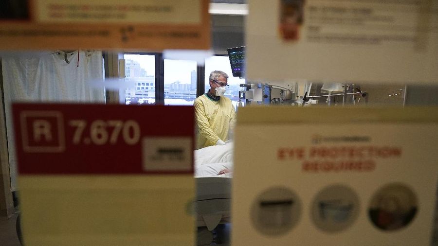 Steve Grove, seorang pendeta di Hennepin County Medical Center, berdoa di kamar pasien COVID-19 di Minneapolis, Jumat (10/12/2021). (AP/Charlie Neibergall)