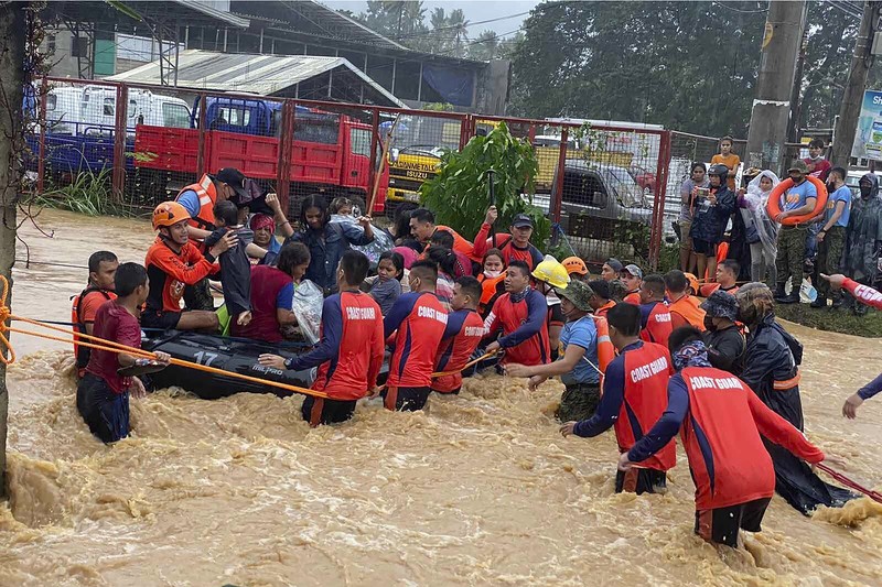 Badai Topan Rai di Filipina Tim penyelamat membantu warga saat banjir yang disebabkan oleh Topan Rai saat mereka dievakuasi ke tempat yang lebih tinggi di Kota Cagayan de Oro, Filipina selatan, Kamis (16/12/2021). Puluhan ribu orang terdampar dievakuasi ke tempat yang aman di Filipina selatan dan tengah ketika Topan Rai mendekati Kamis pada saat pihak berwenang memperingatkan masyarakat untuk menghindari kerumunan setelah infeksi pertama yang disebabkan oleh jenis virus corona dilaporkan di negara itu, kata para pejabat. (Philippine Coast Guard via AP)