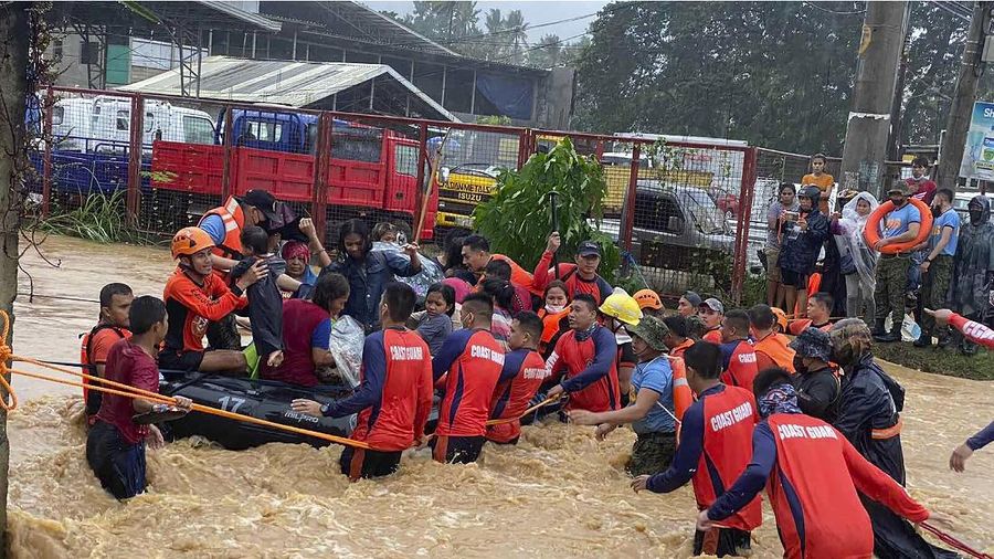 Tim penyelamat membantu warga saat banjir yang disebabkan oleh Topan Rai saat mereka dievakuasi ke tempat yang lebih tinggi di Kota Cagayan de Oro, Filipina selatan, Kamis (16/12/2021). Puluhan ribu orang terdampar dievakuasi ke tempat yang aman di Filipina selatan dan tengah ketika Topan Rai mendekati Kamis pada saat pihak berwenang memperingatkan masyarakat untuk menghindari kerumunan setelah infeksi pertama yang disebabkan oleh jenis virus corona dilaporkan di negara itu, kata para pejabat. (Philippine Coast Guard via AP)