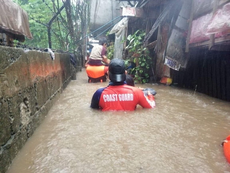 Tim penyelamat membantu warga saat banjir yang disebabkan oleh Topan Rai saat mereka dievakuasi ke tempat yang lebih tinggi di Kota Cagayan de Oro, Filipina selatan, Kamis (16/12/2021). Puluhan ribu orang terdampar dievakuasi ke tempat yang aman di Filipina selatan dan tengah ketika Topan Rai mendekati Kamis pada saat pihak berwenang memperingatkan masyarakat untuk menghindari kerumunan setelah infeksi pertama yang disebabkan oleh jenis virus corona dilaporkan di negara itu, kata para pejabat. (Philippine Coast Guard via AP)