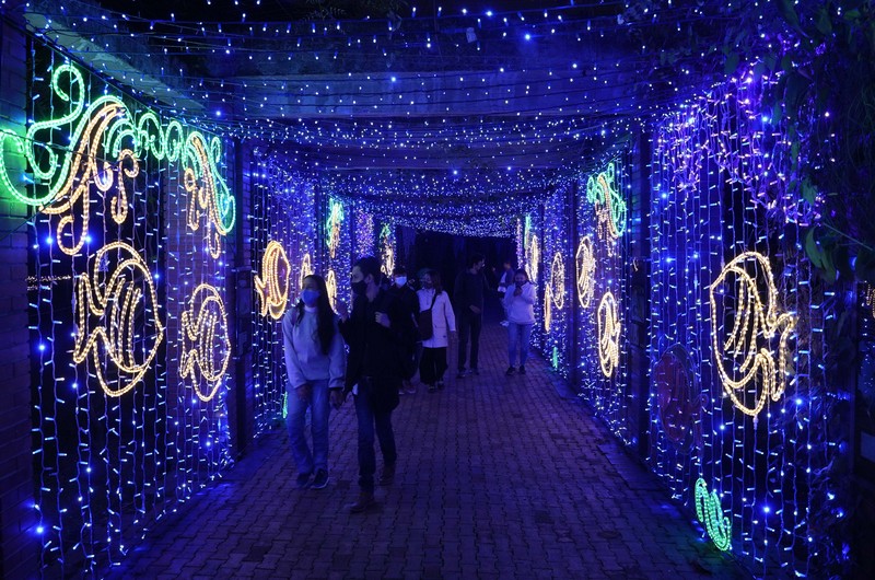 Orang-orang berjalan di jembatan saat lampu Natal menerangi Darsena dei Navigli, lingkungan yang dinamai kanal yang melintasi area Milan, Italia. (AP Photo/Luca Bruno)