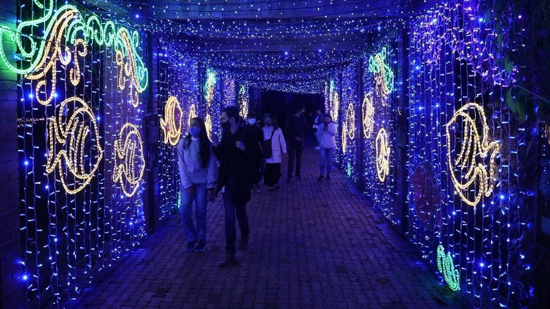 Orang-orang berjalan di jembatan saat lampu Natal menerangi Darsena dei Navigli, lingkungan yang dinamai kanal yang melintasi area Milan, Italia. (AP Photo/Luca Bruno)