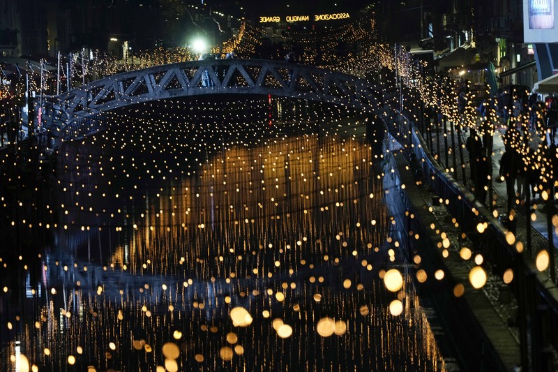 Orang-orang berjalan di jembatan saat lampu Natal menerangi Darsena dei Navigli, lingkungan yang dinamai kanal yang melintasi area Milan, Italia. (AP Photo/Luca Bruno) Orang-orang berjalan di jembatan saat lampu Natal menerangi Darsena dei Navigli, lingkungan yang dinamai kanal yang melintasi area Milan, Italia. (AP Photo/Luca Bruno)