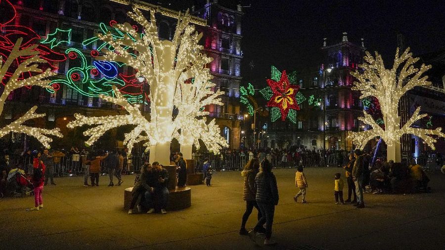 Orang-orang berjalan di jembatan saat lampu Natal menerangi Darsena dei Navigli, lingkungan yang dinamai kanal yang melintasi area Milan, Italia. (AP Photo/Luca Bruno)
