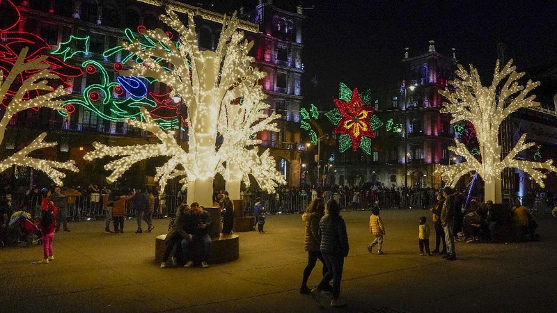 Orang-orang berjalan di jembatan saat lampu Natal menerangi Darsena dei Navigli, lingkungan yang dinamai kanal yang melintasi area Milan, Italia. (AP Photo/Luca Bruno)