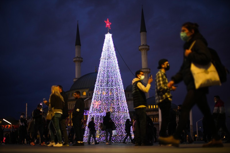 Orang-orang berjalan di jembatan saat lampu Natal menerangi Darsena dei Navigli, lingkungan yang dinamai kanal yang melintasi area Milan, Italia. (AP Photo/Luca Bruno)