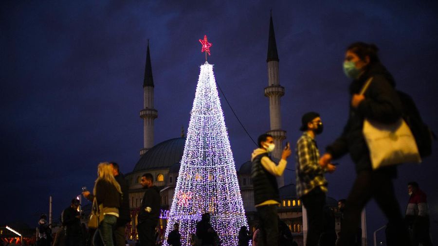 Orang-orang berjalan di jembatan saat lampu Natal menerangi Darsena dei Navigli, lingkungan yang dinamai kanal yang melintasi area Milan, Italia. (AP Photo/Luca Bruno)