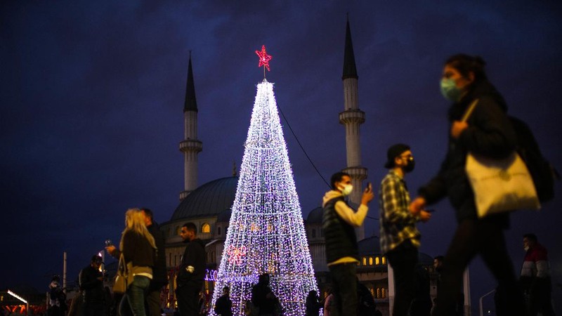 Orang-orang berjalan di jembatan saat lampu Natal menerangi Darsena dei Navigli, lingkungan yang dinamai kanal yang melintasi area Milan, Italia. (AP Photo/Luca Bruno)