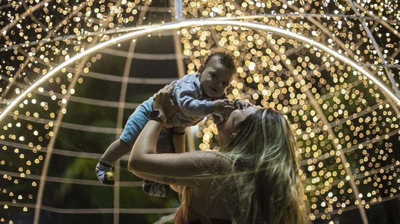 Orang-orang berjalan di jembatan saat lampu Natal menerangi Darsena dei Navigli, lingkungan yang dinamai kanal yang melintasi area Milan, Italia. (AP Photo/Luca Bruno)