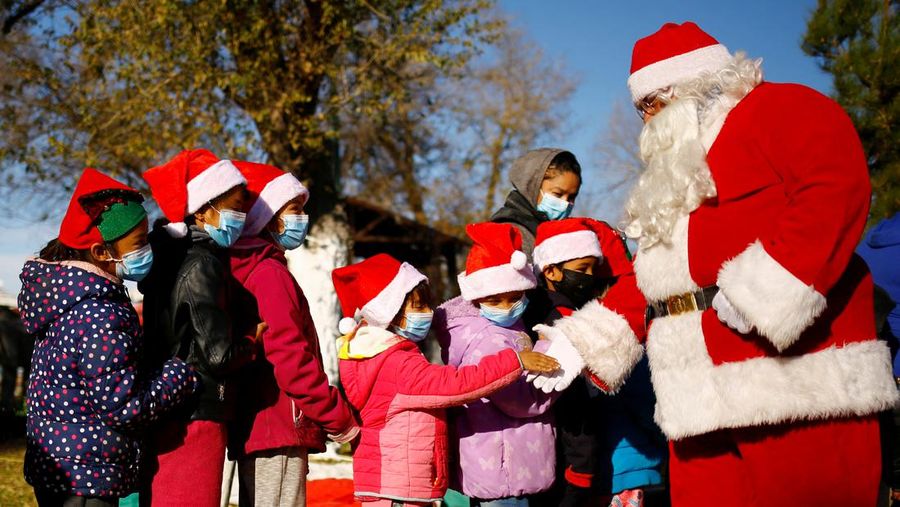 Rodolfo Renteria, a firefighter dressed as Santa Claus, greets children who are queuing during the annual gift-giving event organized by the Fire Department, where items donated throughout the year are given to children in need, in Ciudad Juarez, Mexico December 24, 2021. REUTERS/Jose Luis Gonzalez