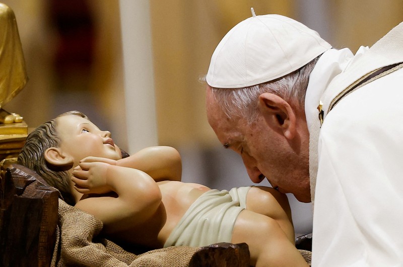 Pope Francis kisses a statue of baby Jesus as he celebrates Christmas Eve Holy Mass in St. Peter's Basilica at the Vatican, December 24, 2021. REUTERS/Guglielmo Mangiapane     TPX IMAGES OF THE DAY