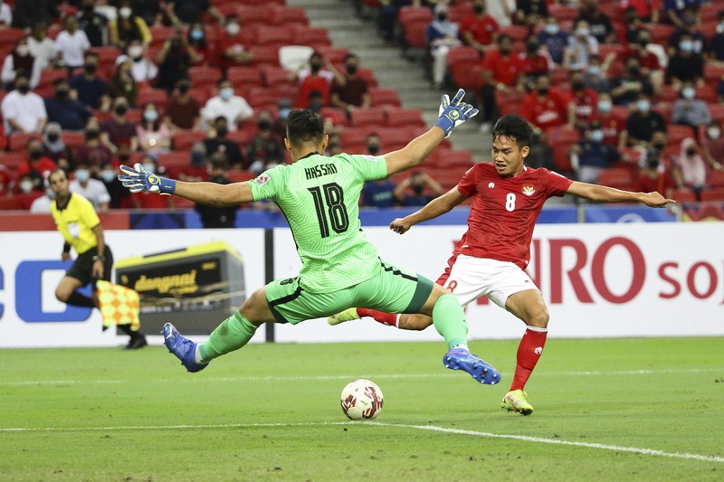 Singapore Soccer Suzuki Cup Hassan Sunny of Singapore, foreground, attempts a block on Witan Sulaeman of Indonesia cross during the AFF Suzuki Cup 2020 semi-final second leg match between Indonesia and Singapore in Singapore, Sunday, Dec. 26, 2021. (AP Photo/Suhaimi Abdullah)