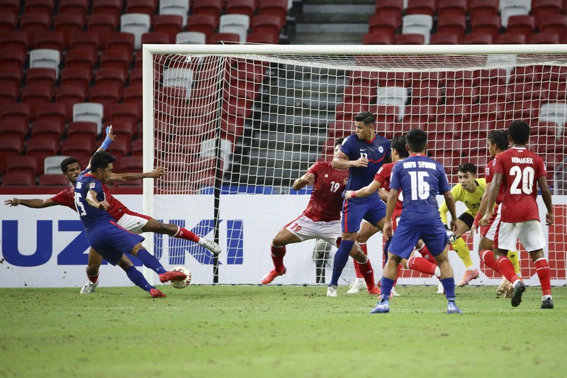 Hassan Sunny of Singapore, foreground, attempts a block on Witan Sulaeman of Indonesia cross during the AFF Suzuki Cup 2020 semi-final second leg match between Indonesia and Singapore in Singapore, Sunday, Dec. 26, 2021. (AP Photo/Suhaimi Abdullah)