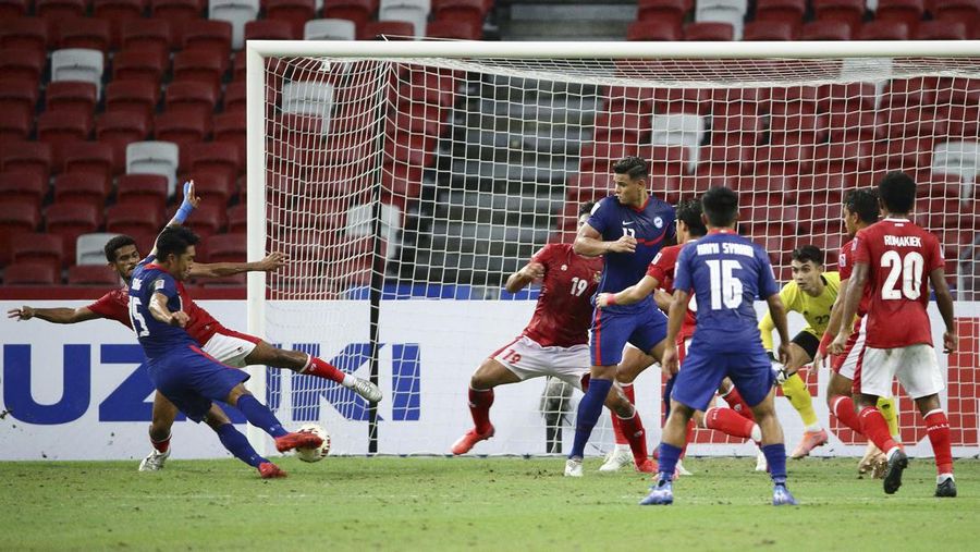 Hassan Sunny of Singapore, foreground, attempts a block on Witan Sulaeman of Indonesia cross during the AFF Suzuki Cup 2020 semi-final second leg match between Indonesia and Singapore in Singapore, Sunday, Dec. 26, 2021. (AP Photo/Suhaimi Abdullah)