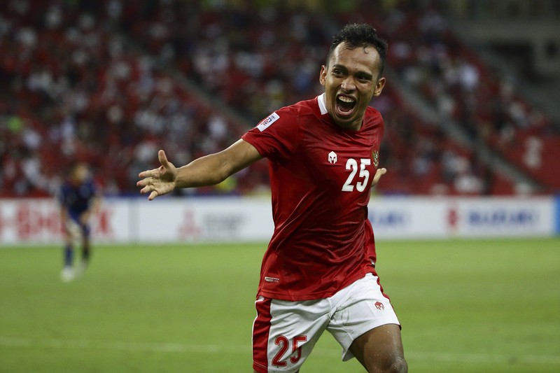 Singapore Soccer Suzuki Cup Hassan Sunny of Singapore, foreground, attempts a block on Witan Sulaeman of Indonesia cross during the AFF Suzuki Cup 2020 semi-final second leg match between Indonesia and Singapore in Singapore, Sunday, Dec. 26, 2021. (AP Photo/Suhaimi Abdullah)
