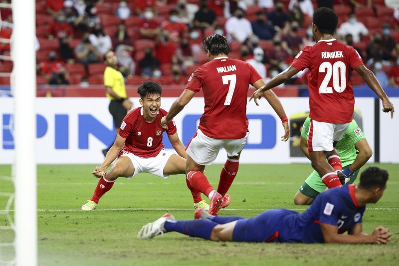 Singapore Soccer Suzuki Cup Hassan Sunny of Singapore, foreground, attempts a block on Witan Sulaeman of Indonesia cross during the AFF Suzuki Cup 2020 semi-final second leg match between Indonesia and Singapore in Singapore, Sunday, Dec. 26, 2021. (AP Photo/Suhaimi Abdullah)