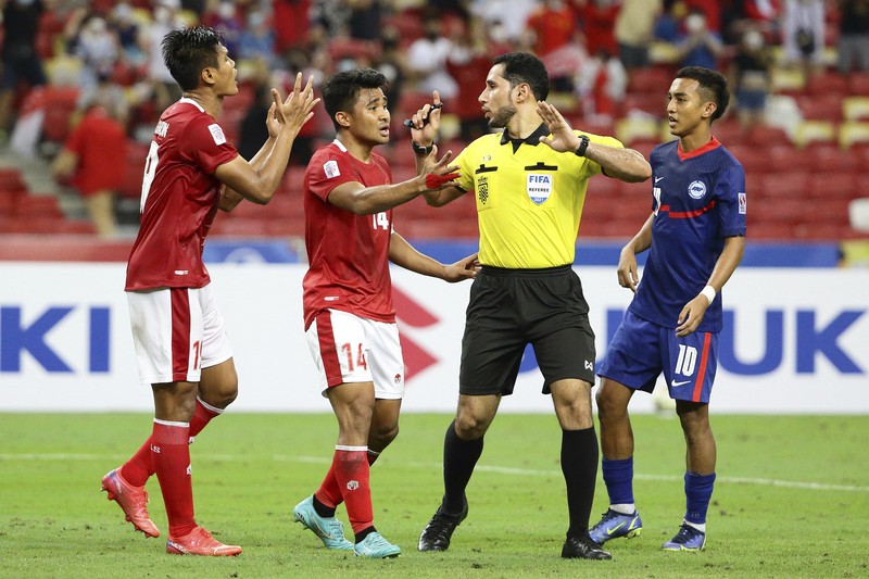 Singapore Soccer Suzuki Cup Hassan Sunny of Singapore, foreground, attempts a block on Witan Sulaeman of Indonesia cross during the AFF Suzuki Cup 2020 semi-final second leg match between Indonesia and Singapore in Singapore, Sunday, Dec. 26, 2021. (AP Photo/Suhaimi Abdullah)