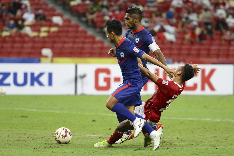 Hassan Sunny of Singapore, foreground, attempts a block on Witan Sulaeman of Indonesia cross during the AFF Suzuki Cup 2020 semi-final second leg match between Indonesia and Singapore in Singapore, Sunday, Dec. 26, 2021. (AP Photo/Suhaimi Abdullah)