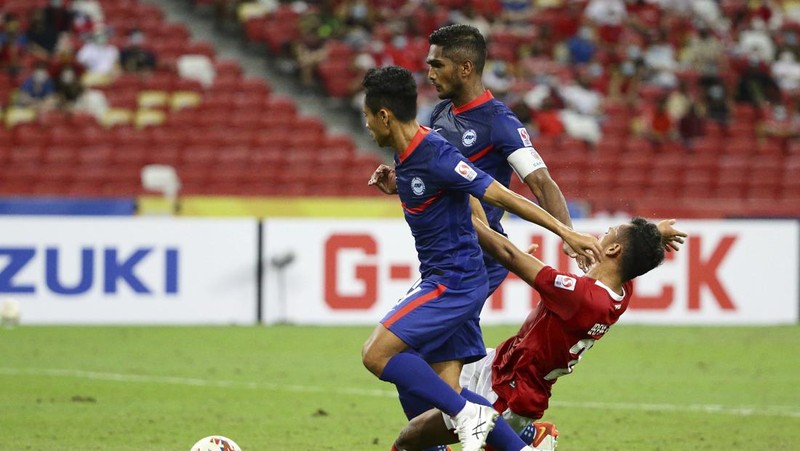 Hassan Sunny of Singapore, foreground, attempts a block on Witan Sulaeman of Indonesia cross during the AFF Suzuki Cup 2020 semi-final second leg match between Indonesia and Singapore in Singapore, Sunday, Dec. 26, 2021. (AP Photo/Suhaimi Abdullah)
