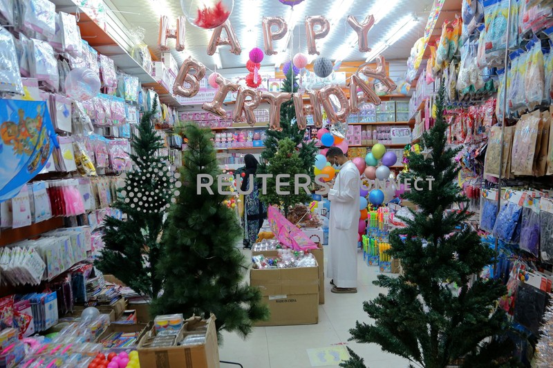 A woman wearing a mask to protect from the coronavirus leaves a gift shop decorated for Christmas and New Year in Jiddah, Saudi Arabia, Friday, Dec. 25, 2020. (AP Photo/Amr Nabil)