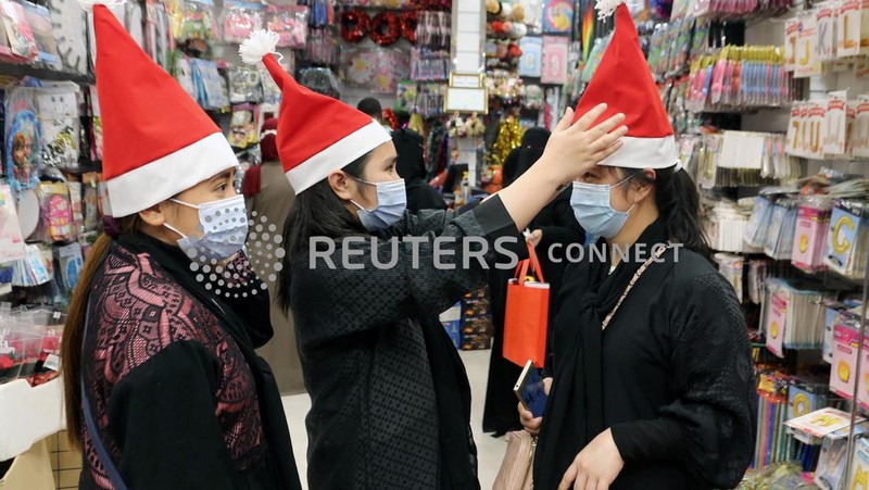 A woman wearing a mask to protect from the coronavirus leaves a gift shop decorated for Christmas and New Year in Jiddah, Saudi Arabia, Friday, Dec. 25, 2020. (AP Photo/Amr Nabil)