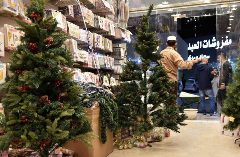 A woman wearing a mask to protect from the coronavirus leaves a gift shop decorated for Christmas and New Year in Jiddah, Saudi Arabia, Friday, Dec. 25, 2020. (AP Photo/Amr Nabil)