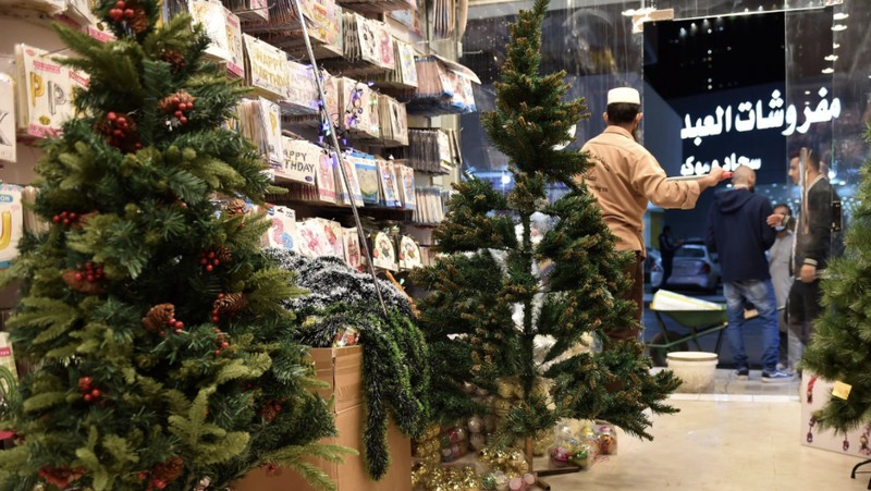 A woman wearing a mask to protect from the coronavirus leaves a gift shop decorated for Christmas and New Year in Jiddah, Saudi Arabia, Friday, Dec. 25, 2020. (AP Photo/Amr Nabil)