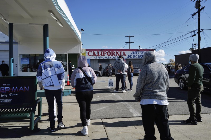 Virus Outbreak California People line up for a free COVID-19 rapid test at a gas station in the Reseda section of Los Angeles on Sunday, Dec. 26, 2021, as California braces for a post-holiday virus surge. (AP Photo/Richard Vogel)