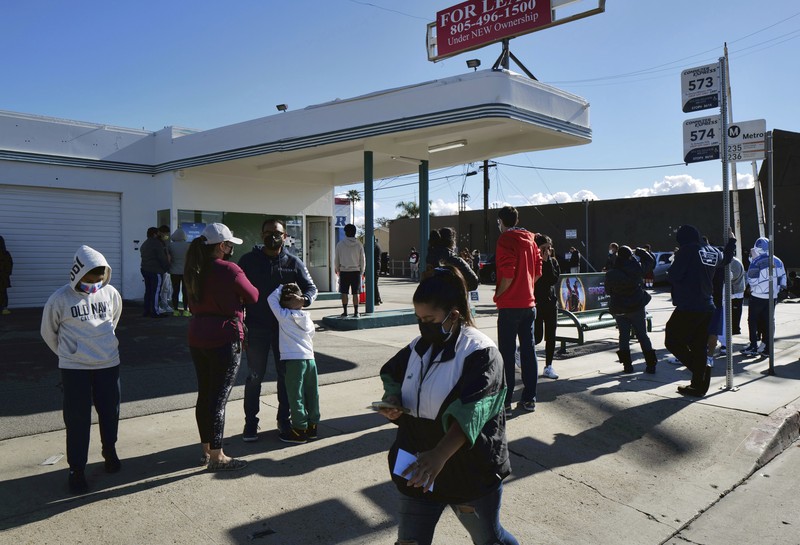 People line up for a free COVID-19 rapid test at a gas station in the Reseda section of Los Angeles on Sunday, Dec. 26, 2021, as California braces for a post-holiday virus surge. (AP Photo/Richard Vogel)