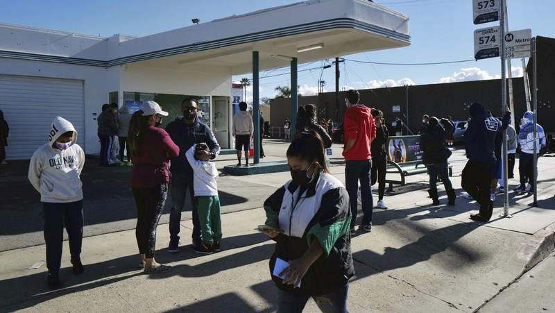 People line up for a free COVID-19 rapid test at a gas station in the Reseda section of Los Angeles on Sunday, Dec. 26, 2021, as California braces for a post-holiday virus surge. (AP Photo/Richard Vogel)