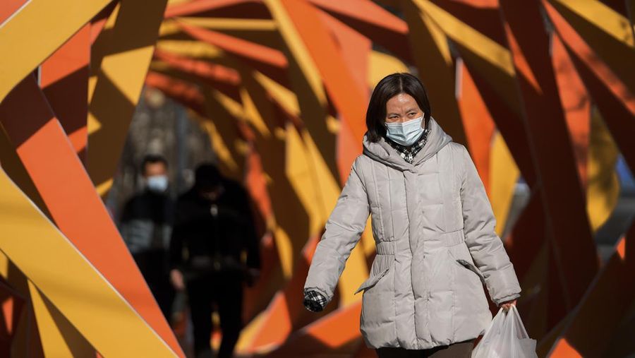 A woman wearing a face mask to help protect from the coronavirus looks as she walks by an art installation depicting a prosperity chamber on display outside a mall in Beijing, Monday, Dec. 27, 2021. (AP Photo/Andy Wong)