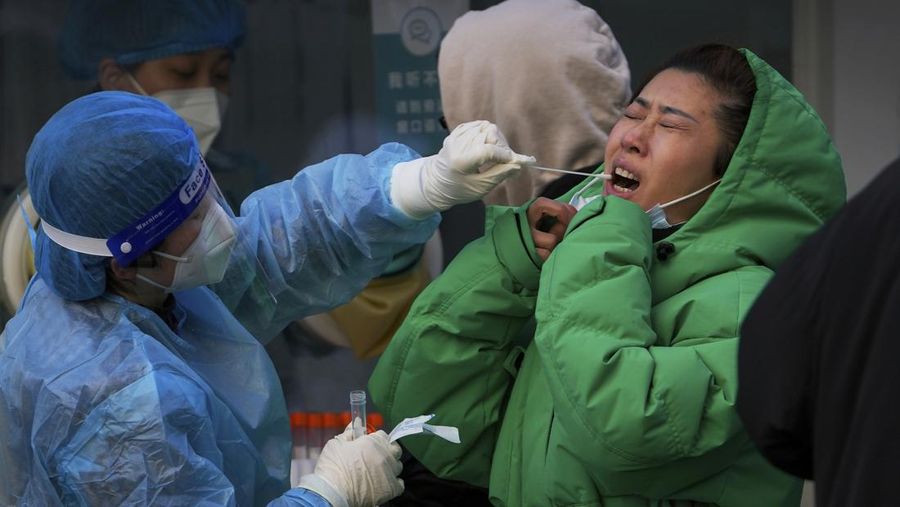 A woman reacts as she gets a swab for the COVID-19 test for traveling requirement at a mobile coronavirus testing facility outside a commercial office buildings in Beijing, Sunday, Dec. 26, 2021. Christmas arrived around the world Saturday amid a surge in COVID-19 infections that kept many families apart, overwhelmed hospitals and curbed religious observances as the pandemic was poised to stretch into a third year. (AP Photo/Andy Wong)