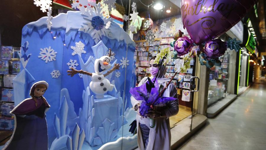A woman wearing a mask to protect from the coronavirus leaves a gift shop decorated for Christmas and New Year in Jiddah, Saudi Arabia, Friday, Dec. 25, 2020. (AP Photo/Amr Nabil)