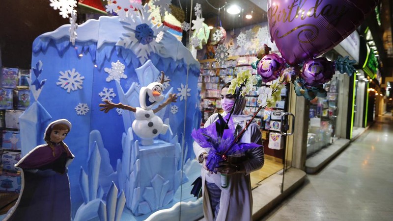 A woman wearing a mask to protect from the coronavirus leaves a gift shop decorated for Christmas and New Year in Jiddah, Saudi Arabia, Friday, Dec. 25, 2020. (AP Photo/Amr Nabil)