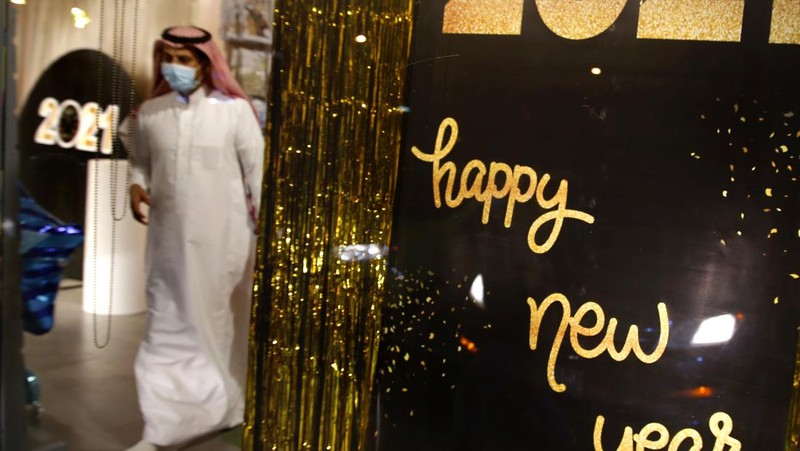 A woman wearing a mask to protect from the coronavirus leaves a gift shop decorated for Christmas and New Year in Jiddah, Saudi Arabia, Friday, Dec. 25, 2020. (AP Photo/Amr Nabil)
