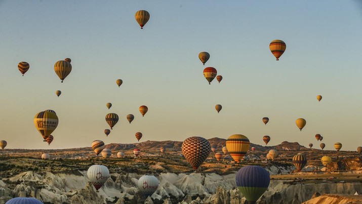 Hot air balloons, carrying tourists, rise into the sky at sunrise in Cappadocia, central Turkey, early Tuesday, Aug. 7, 2018.  Cappadocia has become a favourite site for tourists in hot-air balloons who can slowly drift above the cone-shaped rock formations and then float up over rippled ravines for breathtaking views over the region.(AP Photo/Emrah Gurel)