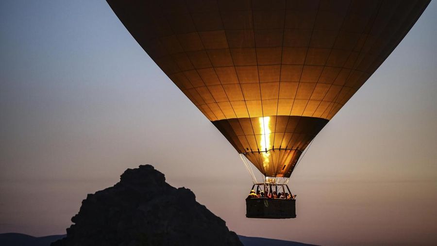 A hot air balloon, carrying tourists, rises into the sky at sunrise in Cappadocia, central Turkey, early Tuesday, Aug. 7, 2018.  Cappadocia has become a favourite site for tourists in hot-air balloons who can slowly drift above the cone-shaped rock formations and then float up over rippled ravines for breathtaking views over the region. (AP Photo/Emrah Gurel)