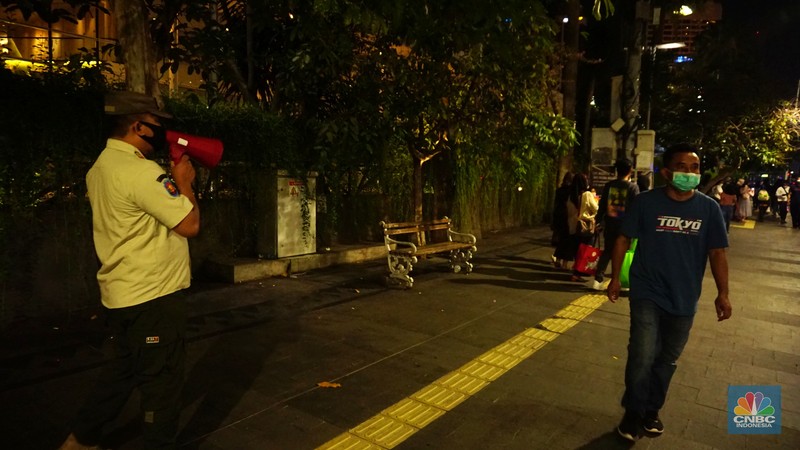Pemberlakukan Crowd Free Night pada saat malam pergantian tahun 2022 Personel Kepolisian berjaga di kawasan Bundaran HI, Jakarta, Jumat (31/12/2021). Kabid Humas Polda Metro Jaya, Kombes Pol Endra Zulpan menerangkan, 1.730 personel disebar ke beberapa titik terutama di ruas jalan yang akan diberlakukan Crowd Free Night pada saat malam pergantian tahun 2022. Kegiatan yang bertujuan untuk mengurangi volume kendaraan pada malam tahun baru itu berlaku pada 31 Desember 2021 sejak pukul 22.00 WIB sampai 1 Januari 2022 pukul 04.00 WIB di 11 ruas jalan di DKI Jakarta. Petugas Satpol PP berusaha membubarkan warga yang masih berada di lokasi kawasan bundaran Hotel Indonesia. (CNBC Indonesia/ Tri Susilo)