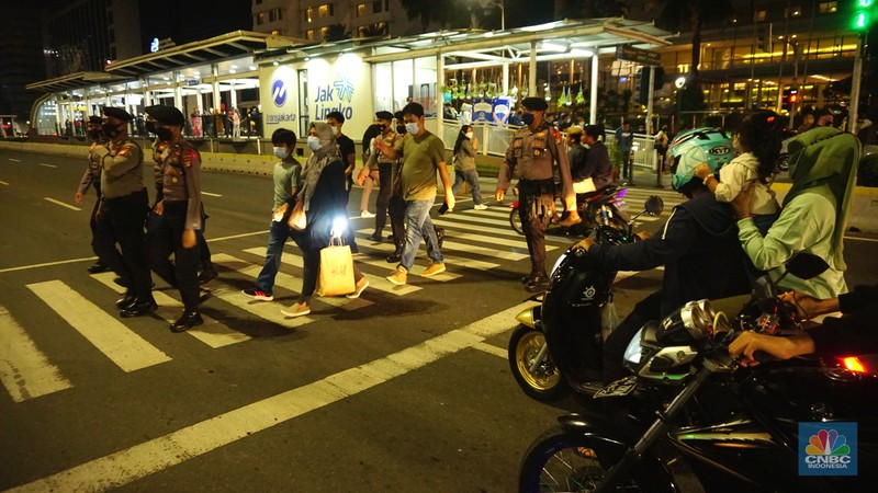 Pemberlakukan Crowd Free Night pada saat malam pergantian tahun 2022 Personel Kepolisian berjaga di kawasan Bundaran HI, Jakarta, Jumat (31/12/2021). Kabid Humas Polda Metro Jaya, Kombes Pol Endra Zulpan menerangkan, 1.730 personel disebar ke beberapa titik terutama di ruas jalan yang akan diberlakukan Crowd Free Night pada saat malam pergantian tahun 2022. Kegiatan yang bertujuan untuk mengurangi volume kendaraan pada malam tahun baru itu berlaku pada 31 Desember 2021 sejak pukul 22.00 WIB sampai 1 Januari 2022 pukul 04.00 WIB di 11 ruas jalan di DKI Jakarta. Petugas Satpol PP berusaha membubarkan warga yang masih berada di lokasi kawasan bundaran Hotel Indonesia. (CNBC Indonesia/ Tri Susilo)
