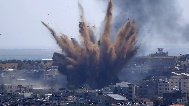 Ledakan dari serangan udara Israel di sebuah bangunan di Kota Gaza melemparkan debu dan puing-puing  ketika Hamas dan Israel bertukar lebih banyak roket dan serangan udara dan kekerasan Yahudi-Arab berkecamuk di seluruh Israel pada akhir bulan suci Ramadhan (13/5/2021). (AP/Hatem Moussa)